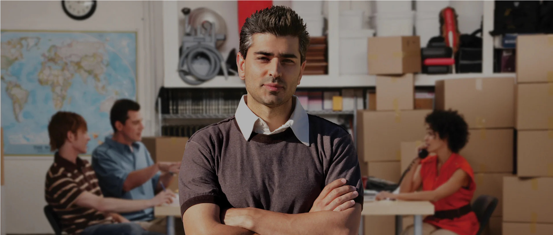 Confident business owner standing with folded arms in front of his team
